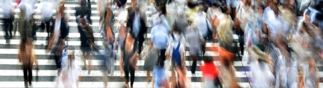 A crowd of people walking across a zebra crossing.